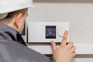 Engineer adjusting thermostat for efficient automated heating system