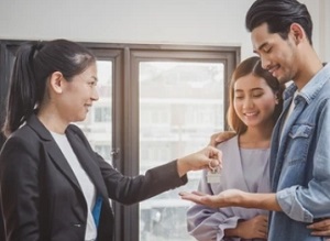 girl offering house key to couple