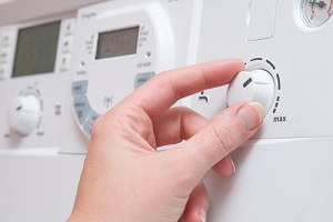 hand adjust the dial controlling water temperature on a white boiler