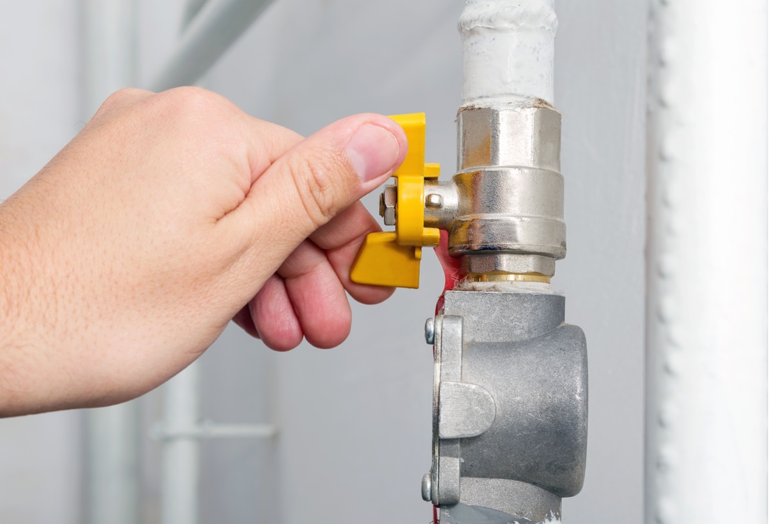 hand opens or closes yellow gas valve on gas pipe at home