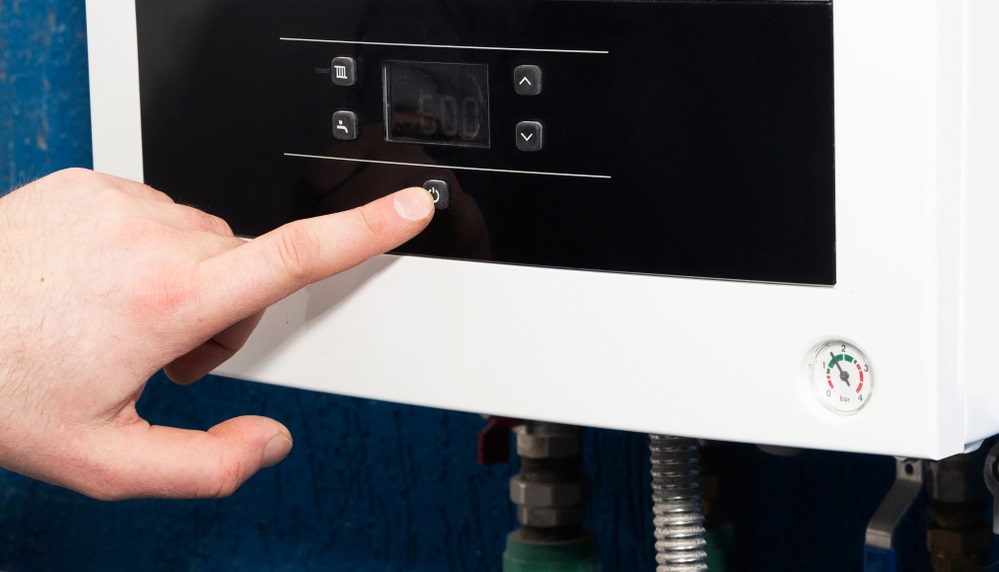 man finger turns on or off the start button of the heating system in the boiler room