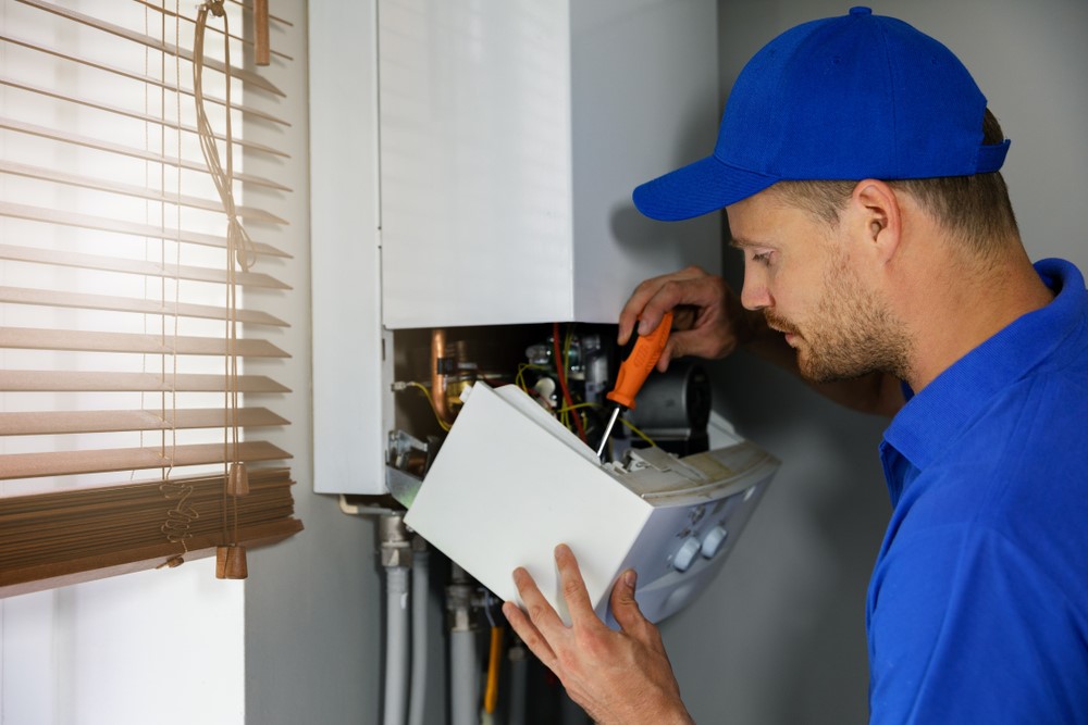 man repairing boiler with screwdriver