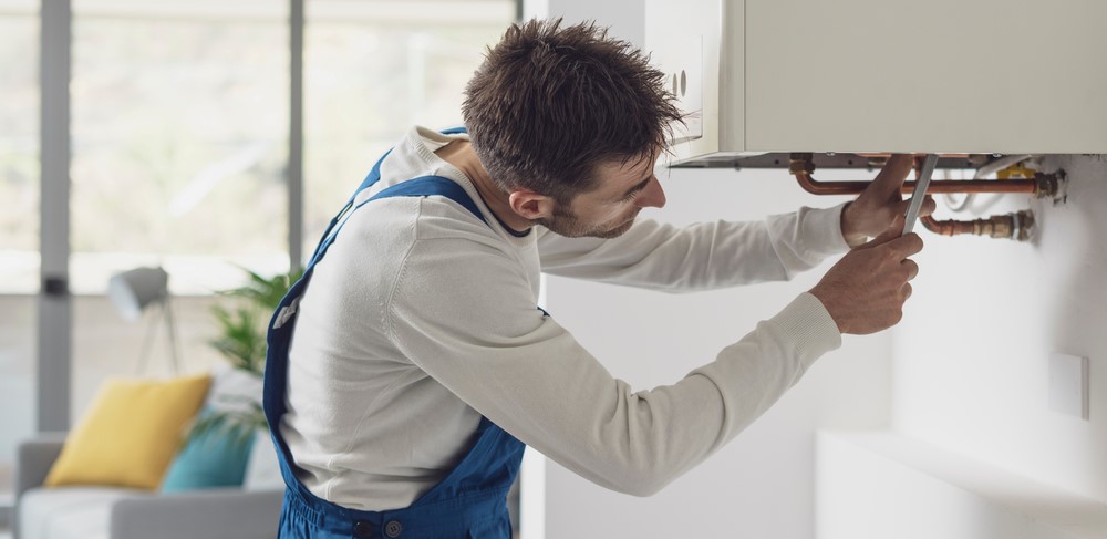 man tightening screw of boiler