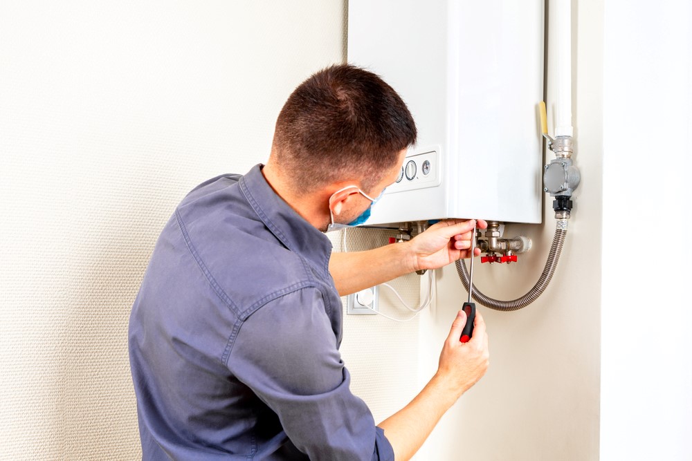 man using screw driver while repairing boiler