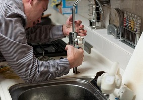 plumber fixing kitchen faucet