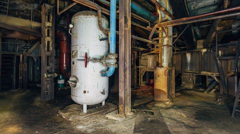 rusty pipeline and vats in underground cellar of abandoned factory