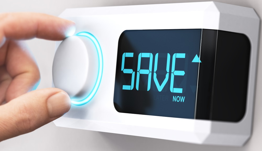 turning a thermostat knob to increase savings by decreasing energy consumption